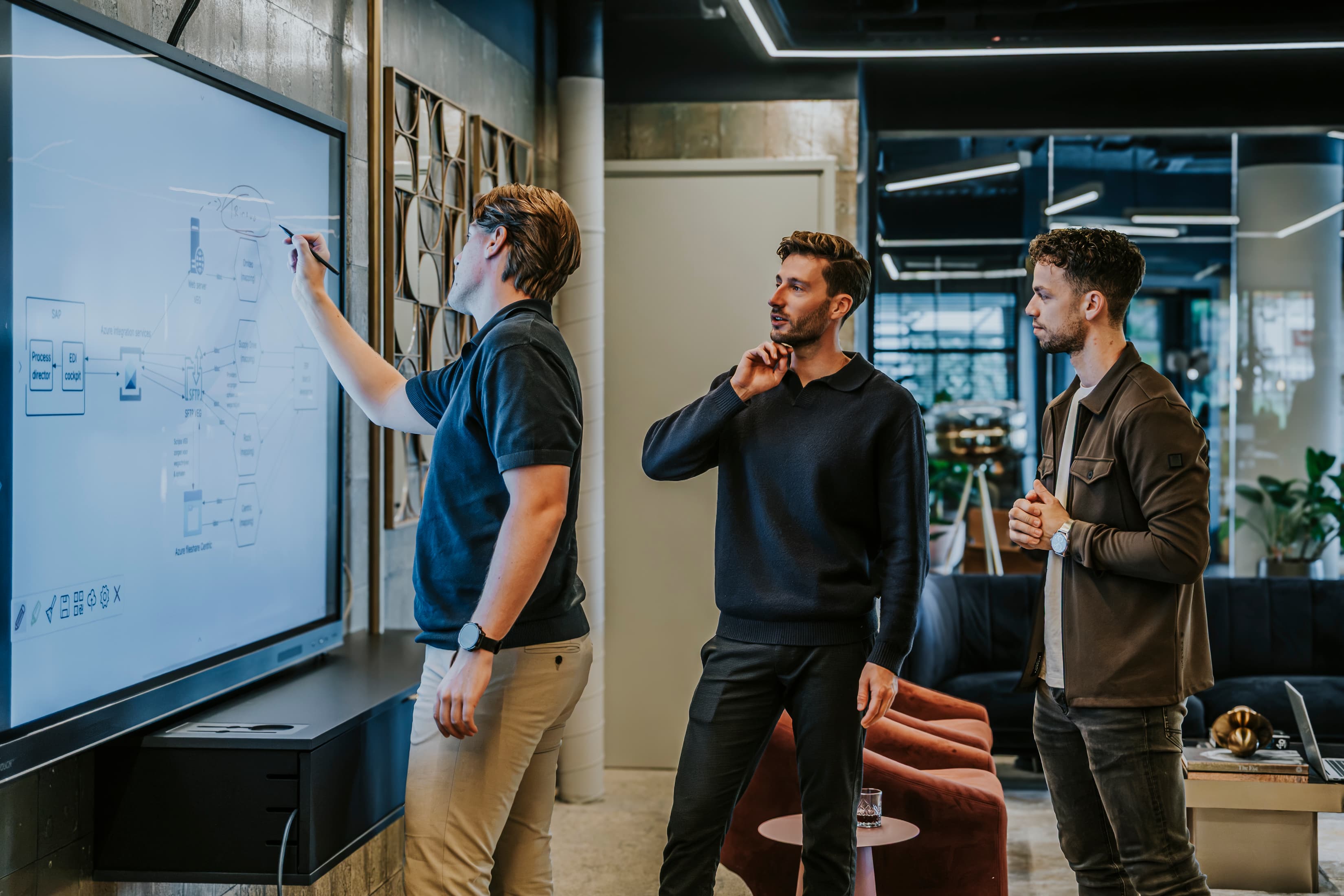 Het Trinovo-team overlegt bij een whiteboard tijdens een werksessie